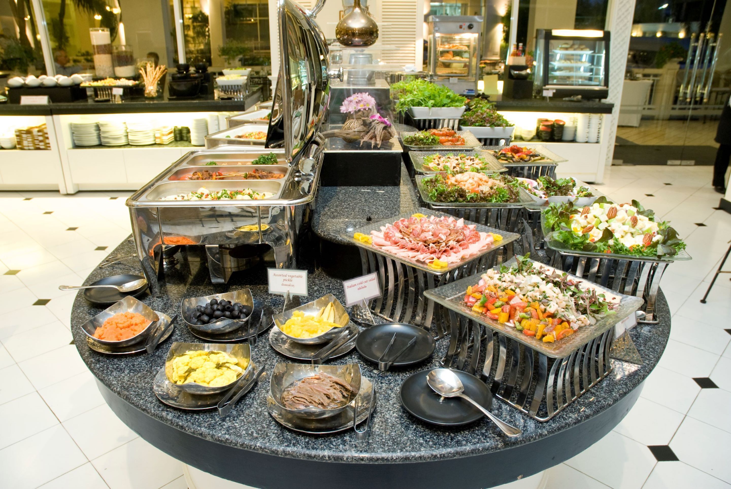 Un bufé con distintas estaciones de comida, que ofrecen ensaladas, carnes y mariscos.