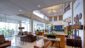 Um hall amplo com pé-direito alto, um candelabro e diversas opções de assentos, incluindo sofás e cadeiras.