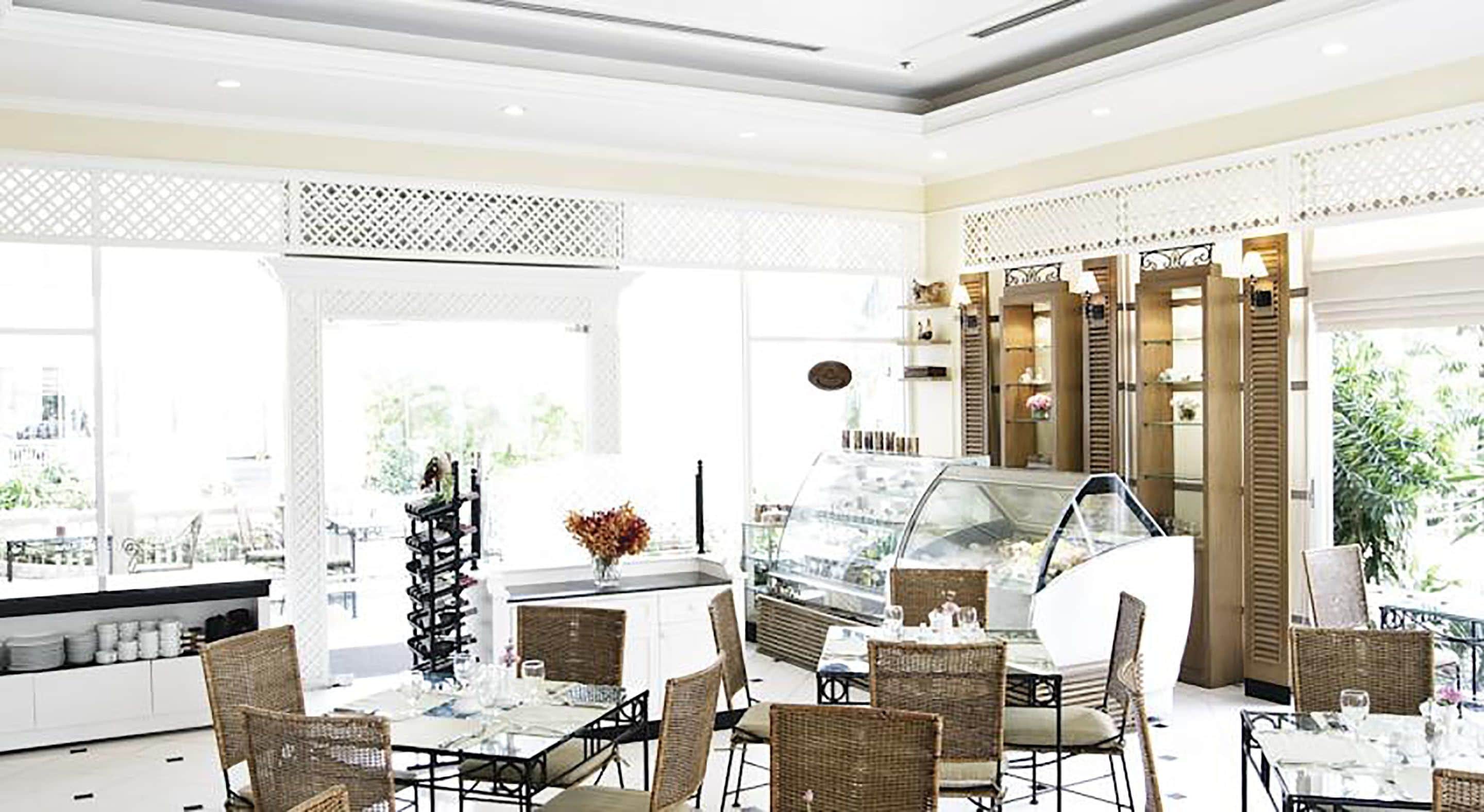 Un restaurant moderne doté d’un présentoir central où sont exposées les différentes sortes de glaces, de meubles en osier et de grandes fenêtres offrant une vue sur la ville.