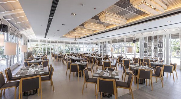 A spacious restaurant with high ceilings, large windows, and modern lighting fixtures.