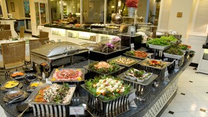Buffet com diversas opções de comida, incluindo saladas, carnes e frutos do mar.