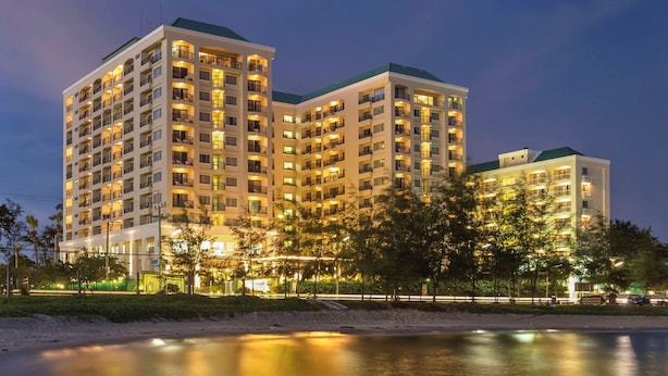 Um hotel com várias andares e varandas, situado perto da orla.