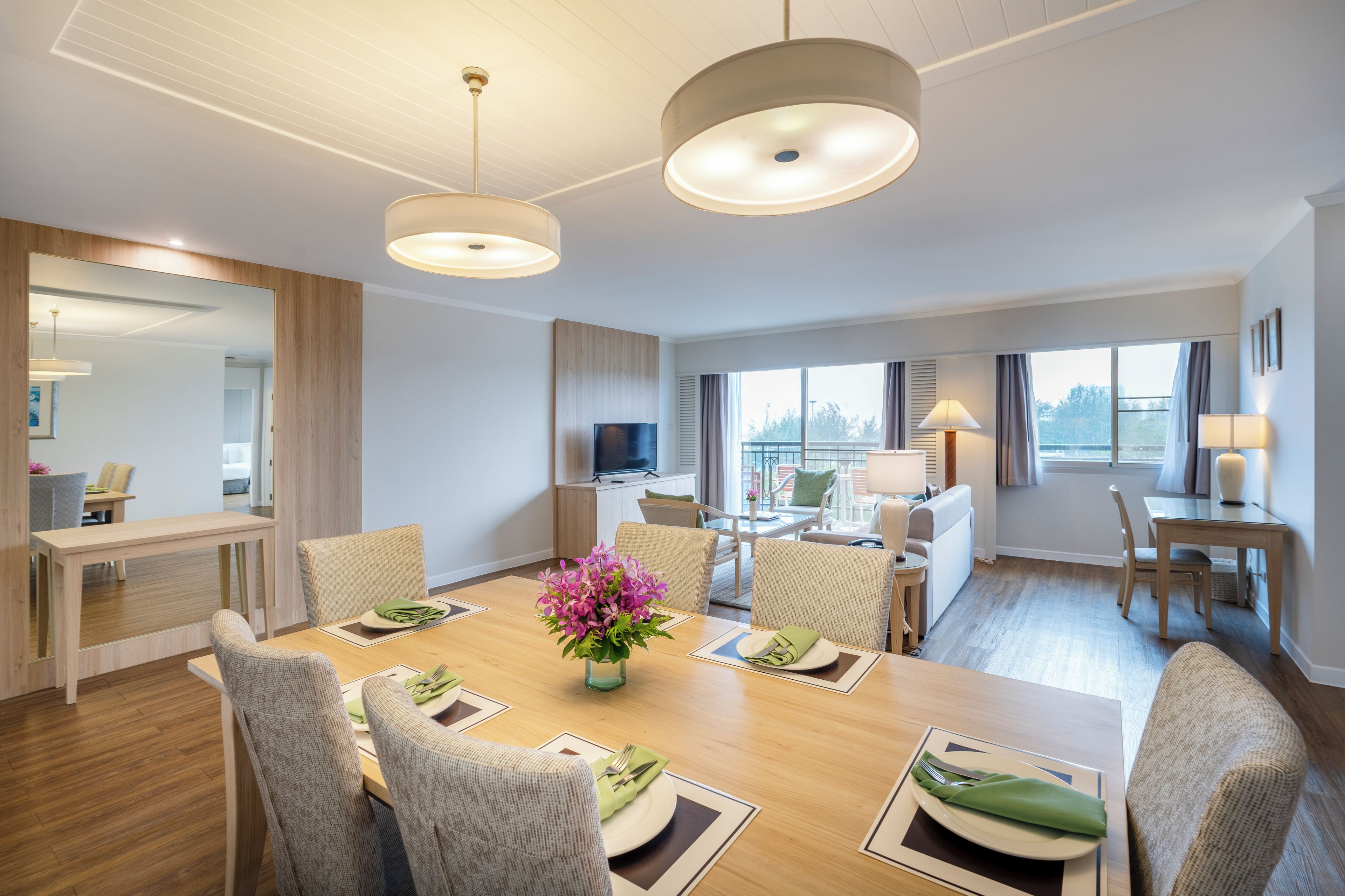 A modern hotel room with a dining area, a living space, and a balcony with a view.