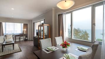 Quarto de hotel moderno com área de refeições, uma janela grande com vista e um espaço de estar acolhedor.