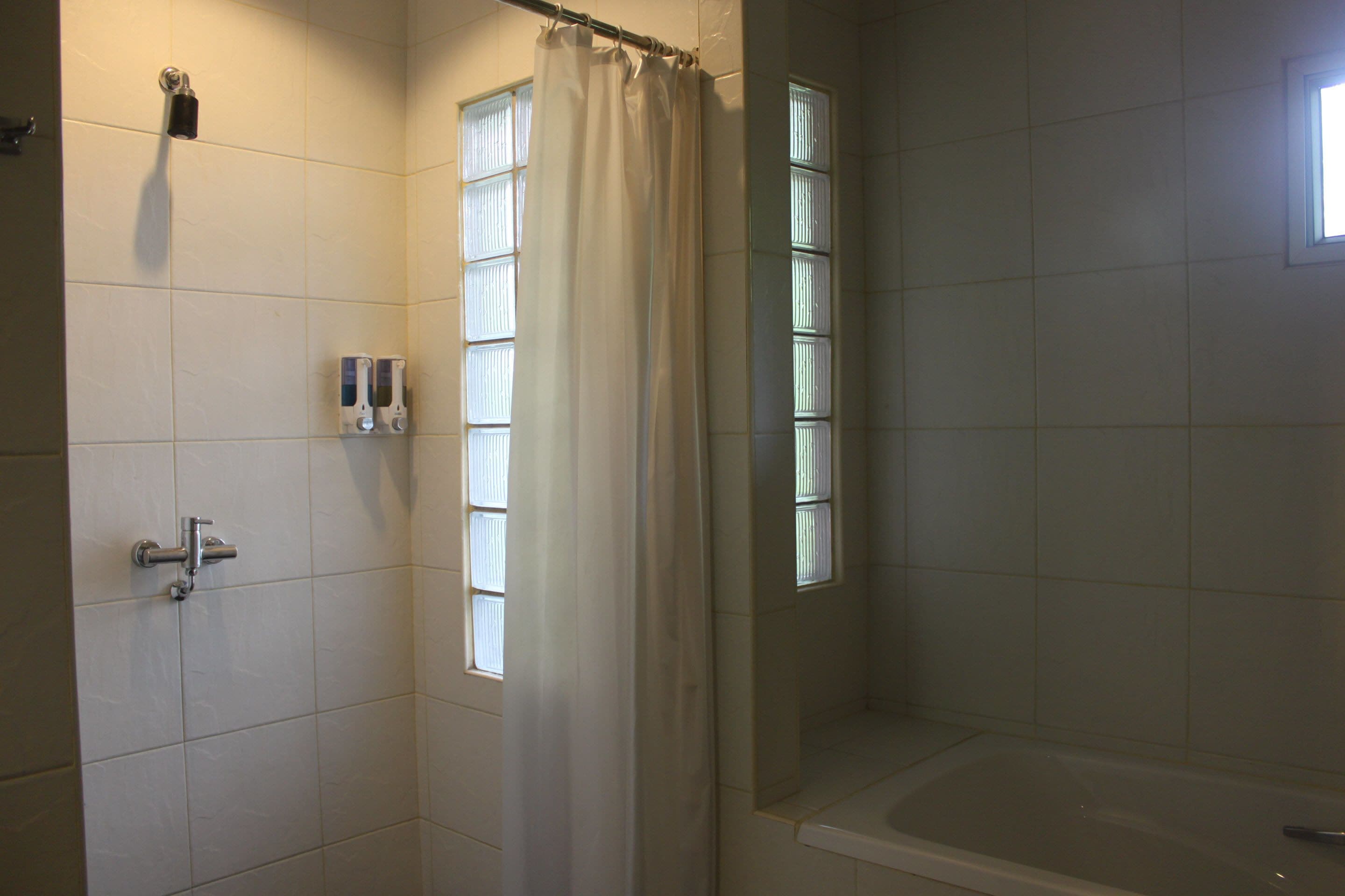 A bathroom with a bathtub, a shower curtain, and a window.
