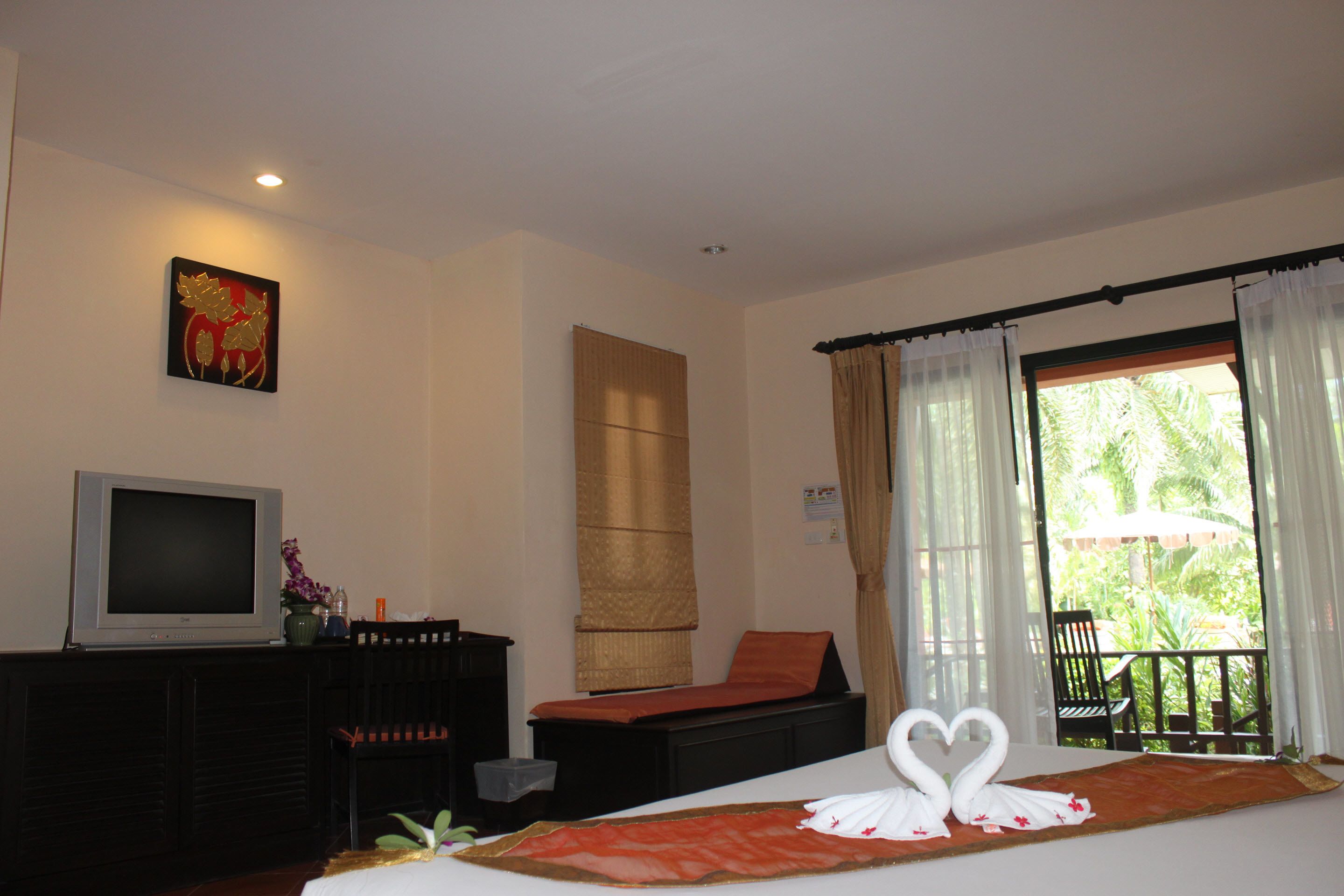 Une chambre d’hôtel avec un lit, une télévision, un bureau et une fenêtre avec des rideaux.