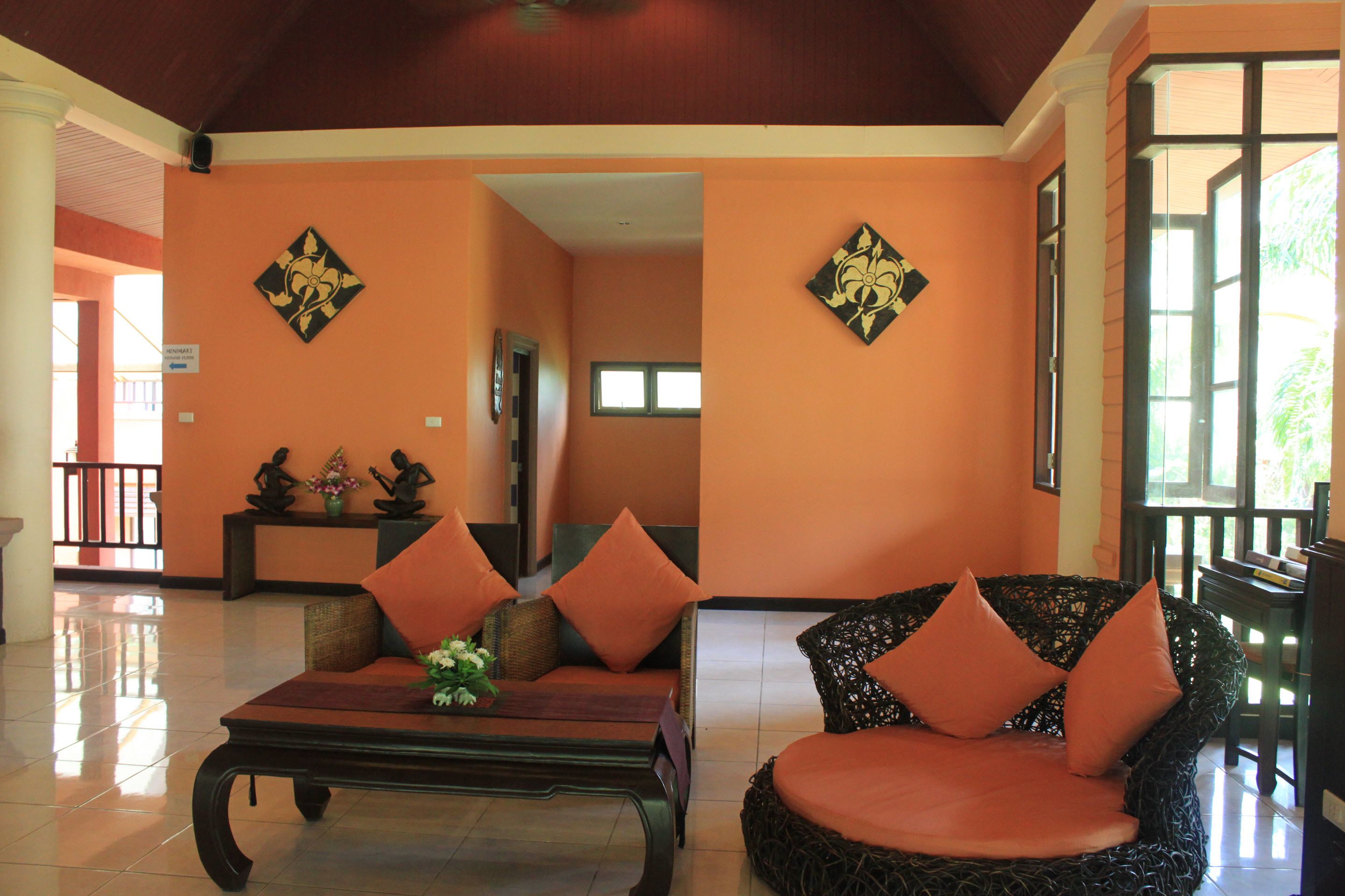 A spacious lobby with a high ceiling, a central seating area with a sofa and armchairs, and a decorative wall with a floral pattern.