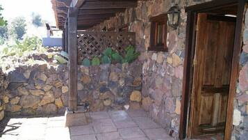 A stone-walled building with a wooden door and a lattice screen.