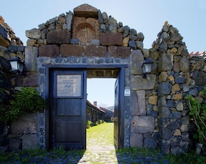 A rustic stone archway leading to a hotel entrance with a sign indicating it is a rural hotel.