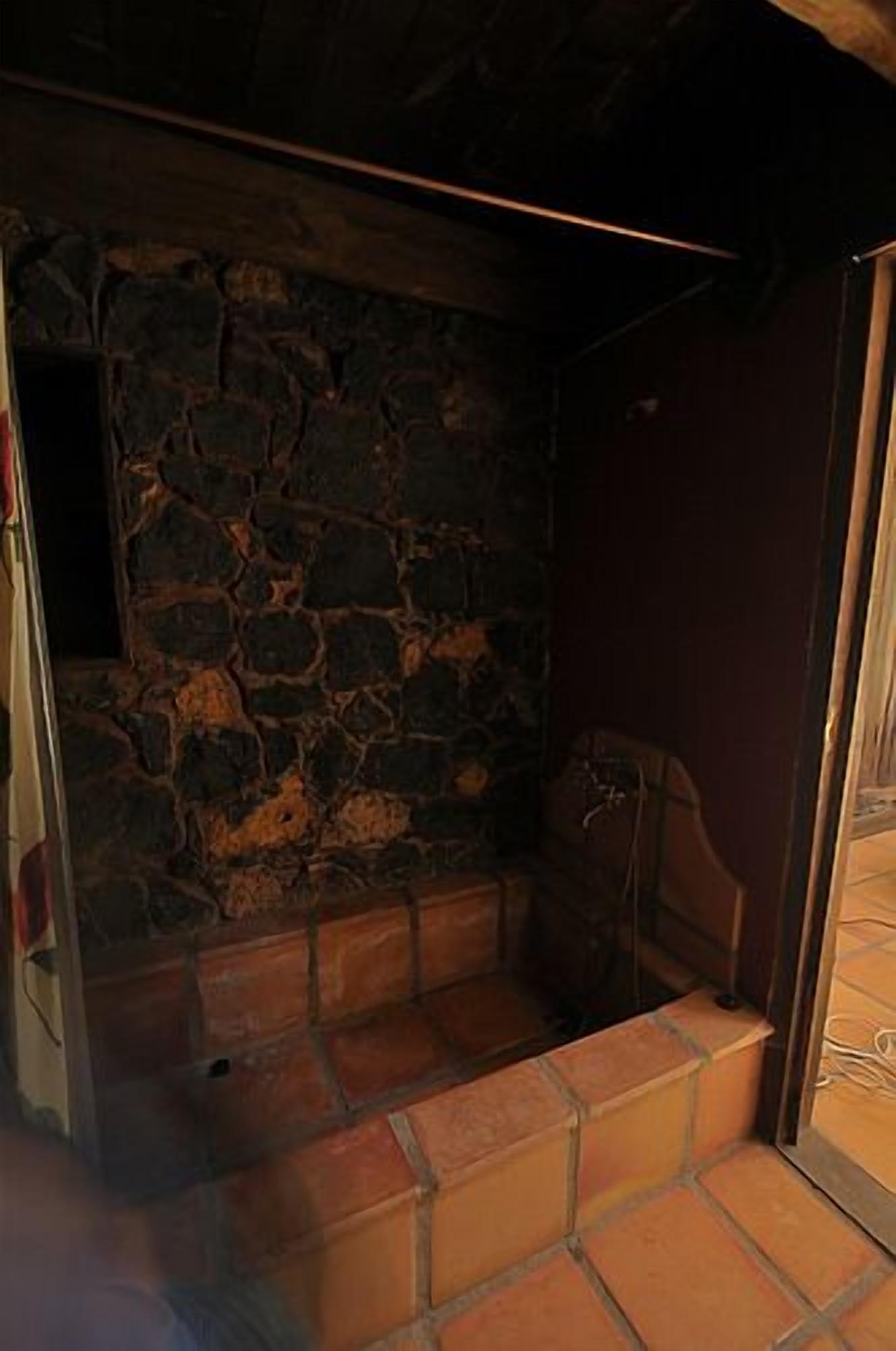 A stone-walled bathroom with a tiled floor and a wooden door.