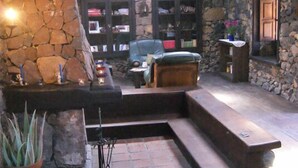 A cozy loft-style living area with a stone wall, leather furniture, and a stone fireplace. - Hotel Rural Caserio Los Partidos (El Tanque)