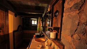 Un baño rústico con un lavamanos de madera, un espejo y un perchero para toallas.
