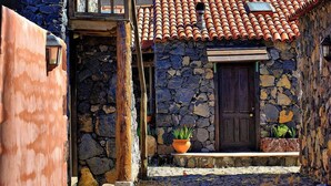 Un edificio de piedra con tejado de tejas, puerta de madera y plantas en macetas en los escalones.