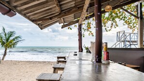 A beachside restaurant with wooden tables and benches, overlooking the ocean. - Kokotel Khao Lak Lighthouse (Takua Pa)