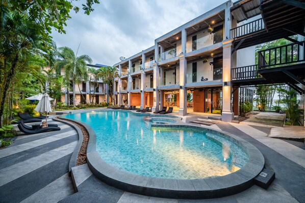 Een buitenzwembad, parasols bij het zwembad en ligstoelen