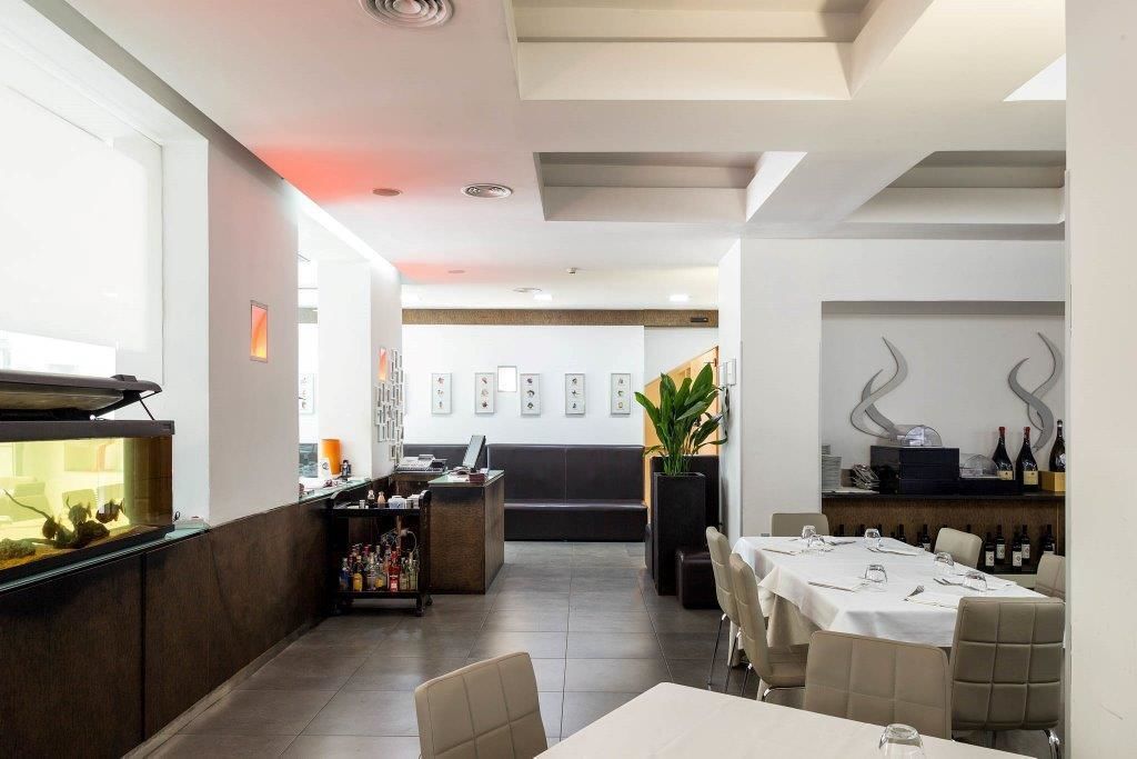 Un restaurante moderno con barra, capacidad para 10 personas y una pared decorativa con fotografías enmarcadas.
