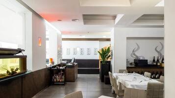 Un restaurante moderno con barra, capacidad para 10 personas y una pared decorativa con fotografías enmarcadas.