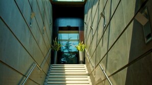 Una escalera estrecha con barandales de metal que conduce a una puerta en la parte superior.