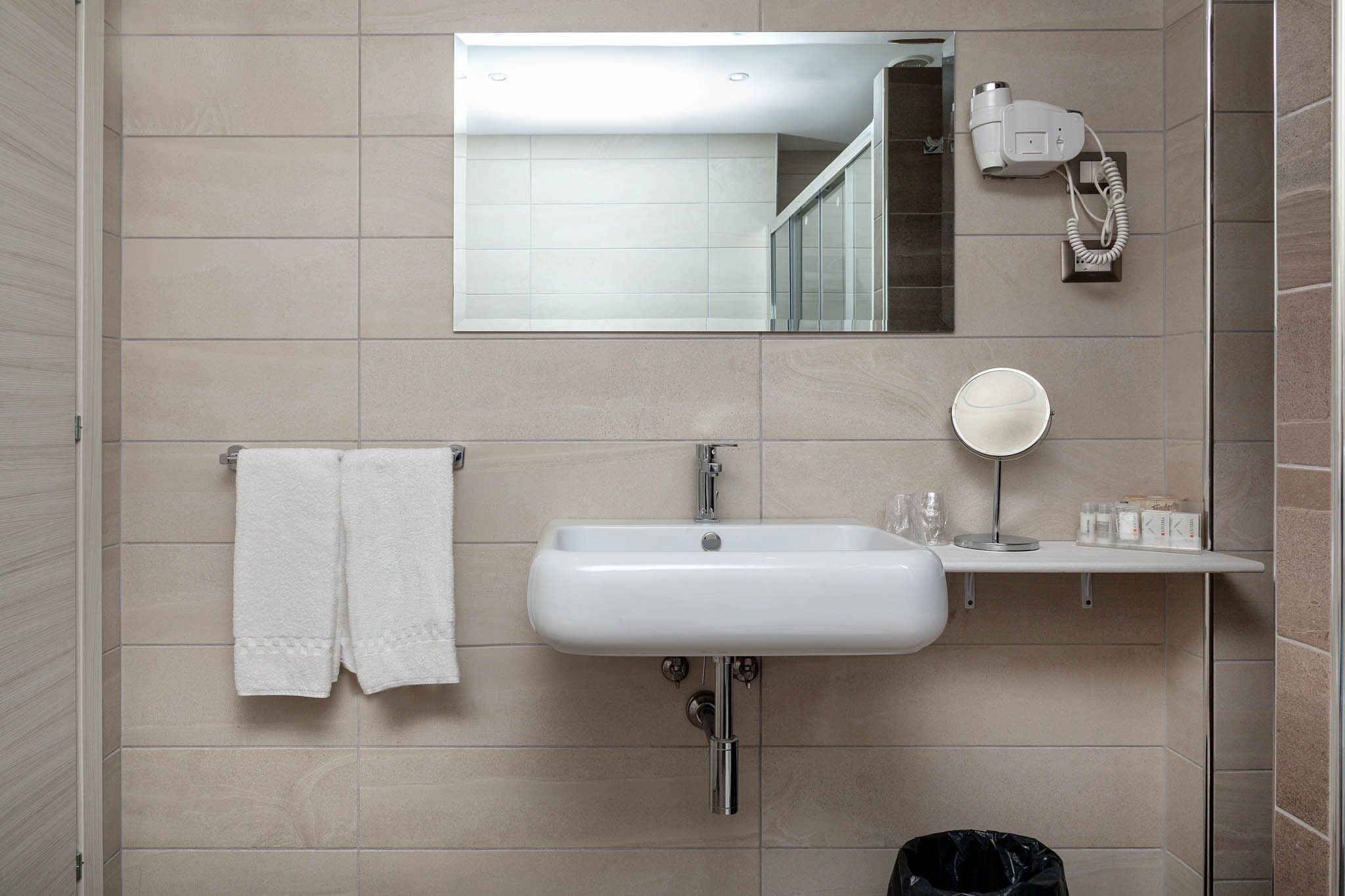 A bathroom with a white sink, a mirror, and a towel rack.