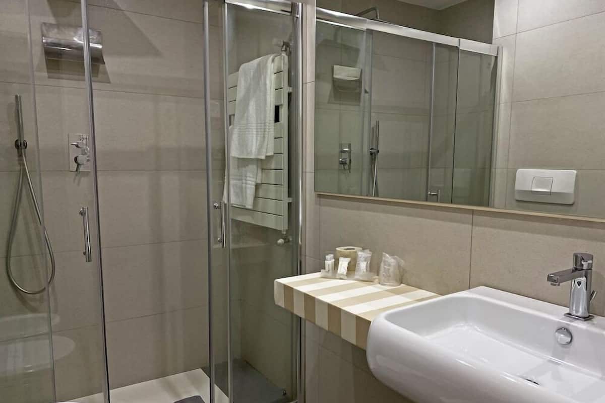 A modern bathroom with a glass-enclosed shower, a white sink, and a mirror above the sink.