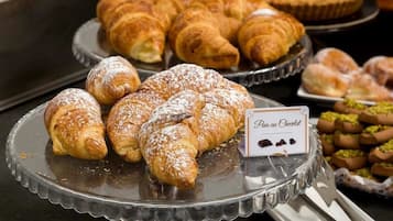 Variedad de pasteles a la vista, incluyendo croissants y un letrero que indica 'Pain au Chocolat'.