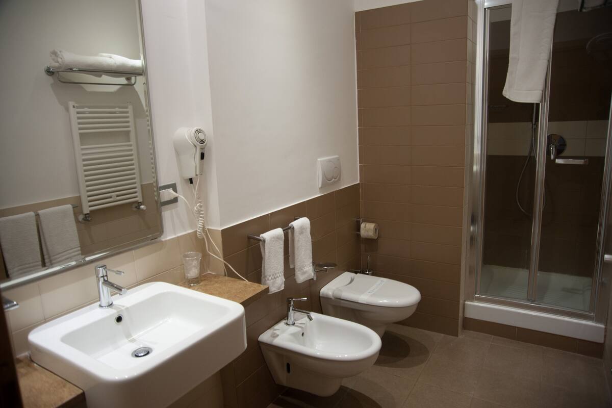 A bathroom with a sink, bidet, and a glass-enclosed shower.