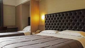 A hotel room with a large bed, a smaller bed, a desk, and a chair.