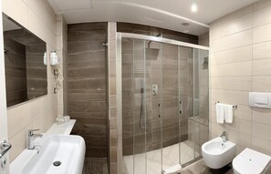 Ein modernes Badezimmer mit einer Duschkabine aus Glas, zwei Waschbecken und einem Bidet.