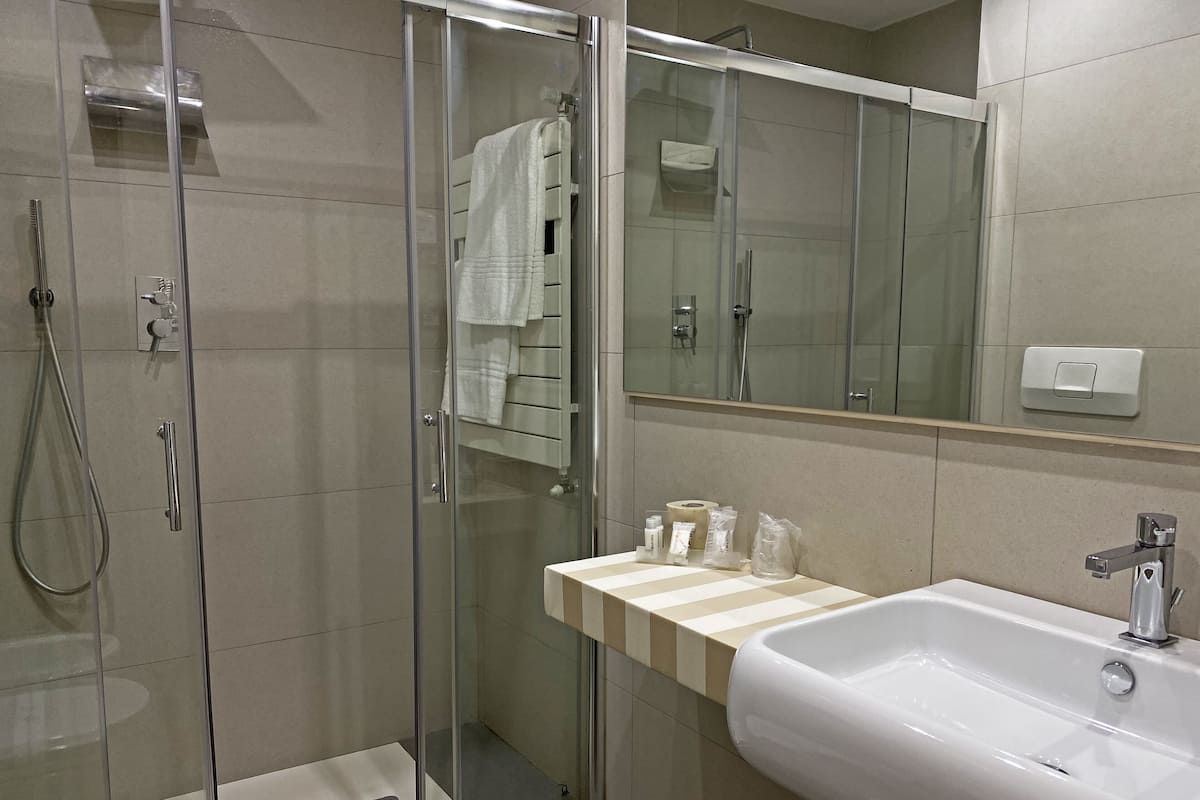 A modern bathroom with a glass-enclosed shower, a white sink, and a mirror above the sink.