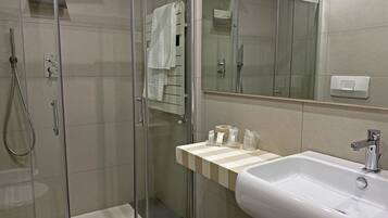 A modern bathroom with a glass-enclosed shower, a white sink, and a mirror above the sink.