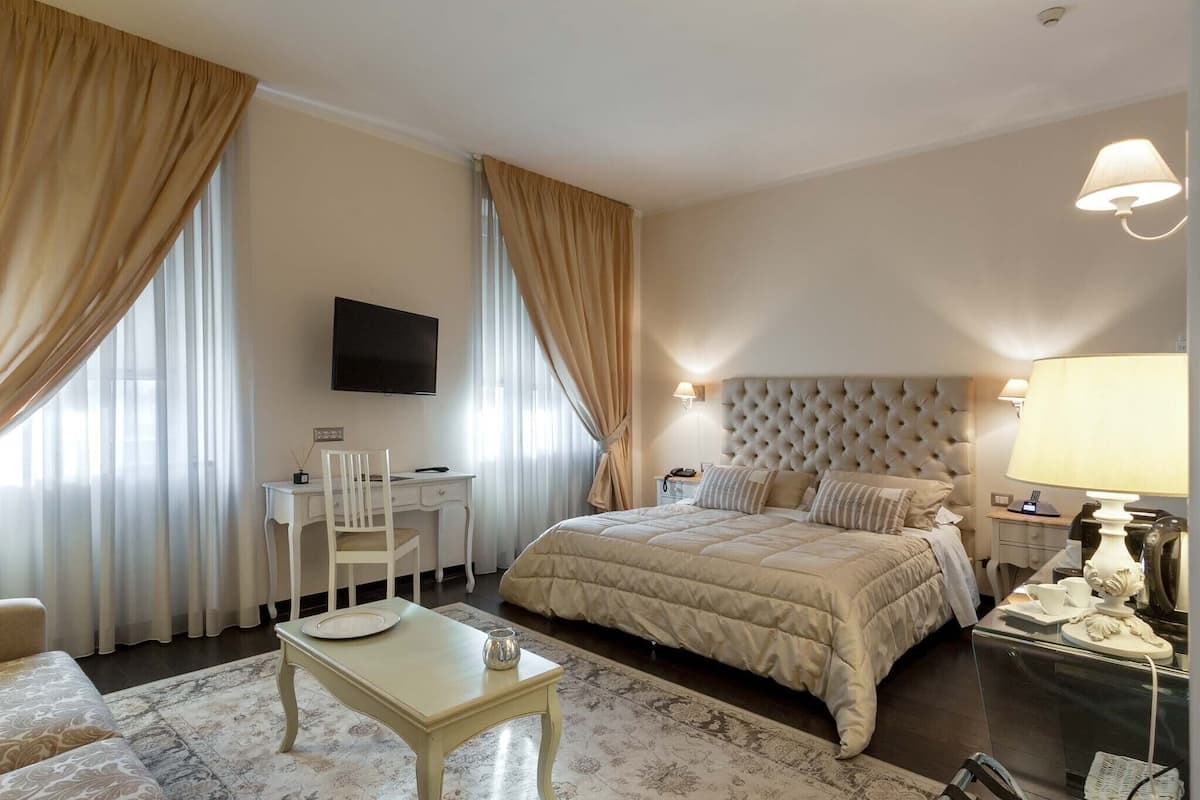A hotel bedroom with a large bed, a desk, a chair, and a television on the wall.