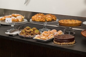 Ein reichhaltiges Buffet mit verschiedenen Backwaren und Desserts, darunter Croissants, ein Kuchen und eine Schokoladentorte.