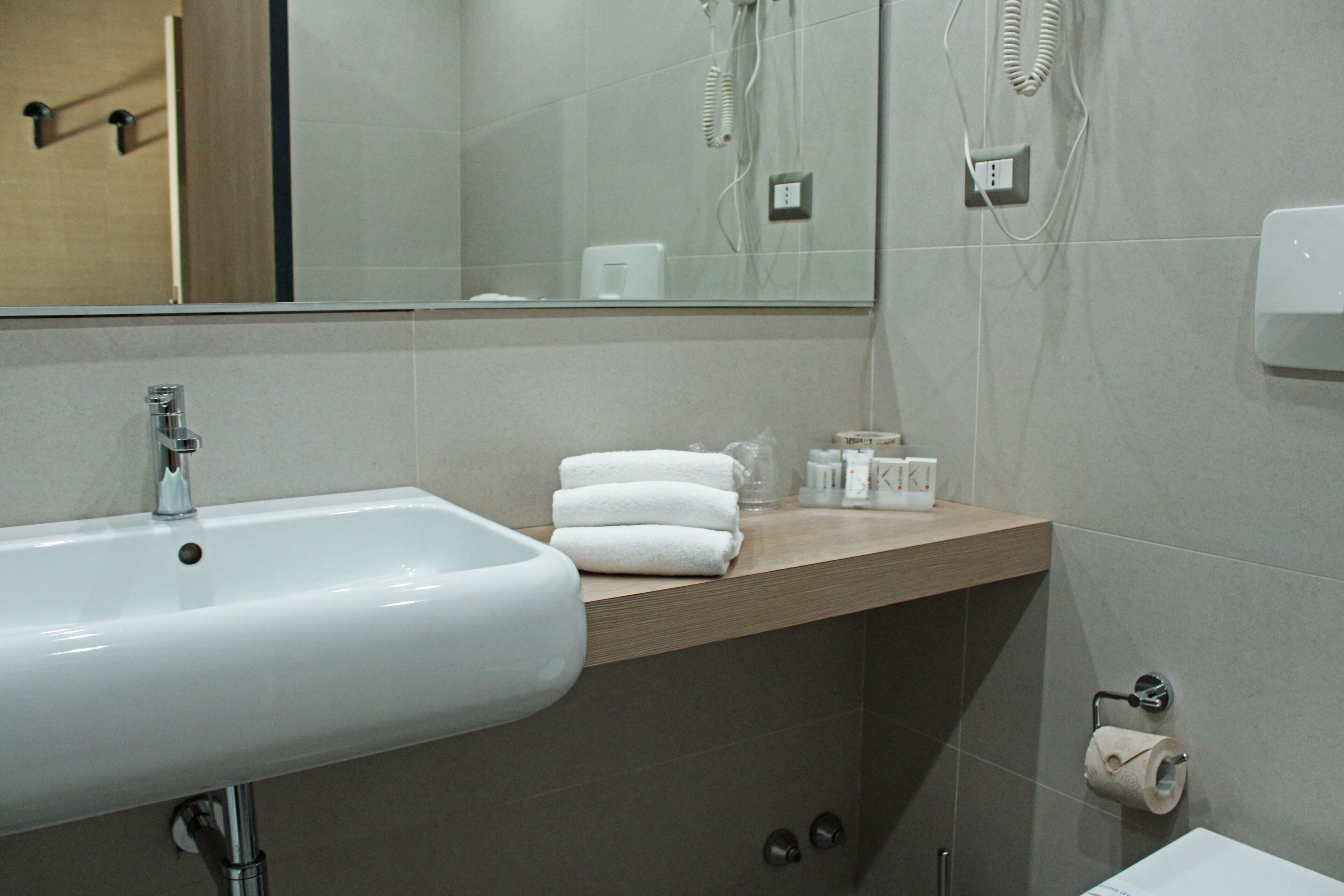A modern bathroom with a white sink, a mirror, and a towel rack.