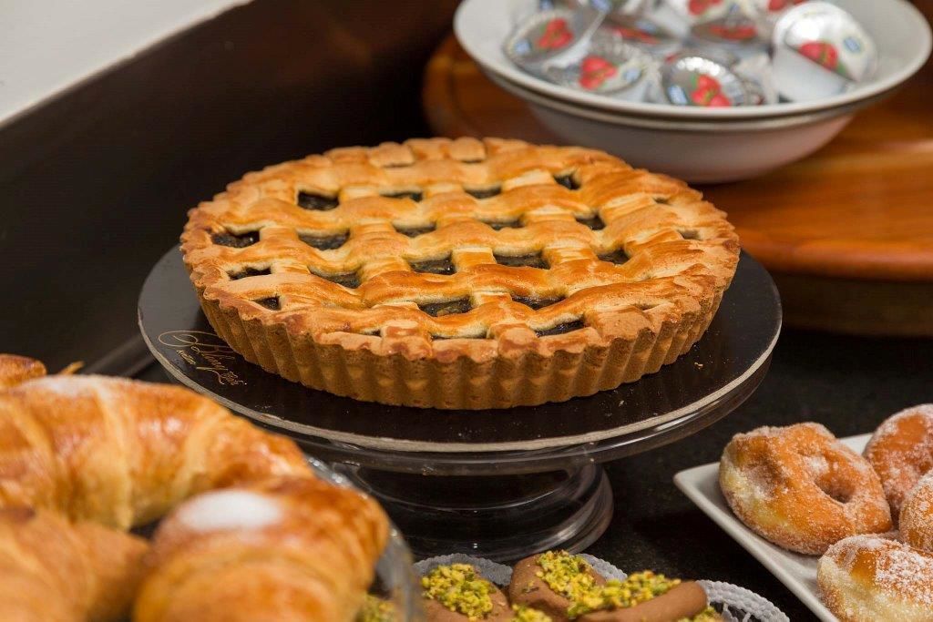 Ein Kuchen auf einem schwarzen Teller mit Rutennetz, umgeben von Gebäck und einer Schale Bonbons.