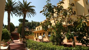 A courtyard with palm trees, a staircase, and a building with balconies.
