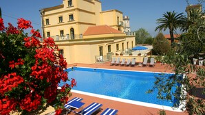 A pool area with lounge chairs and a building in the background.