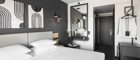 Ein modernes Hotelzimmer mit einem großen Bett, einem Schreibtisch und einem Spiegel.