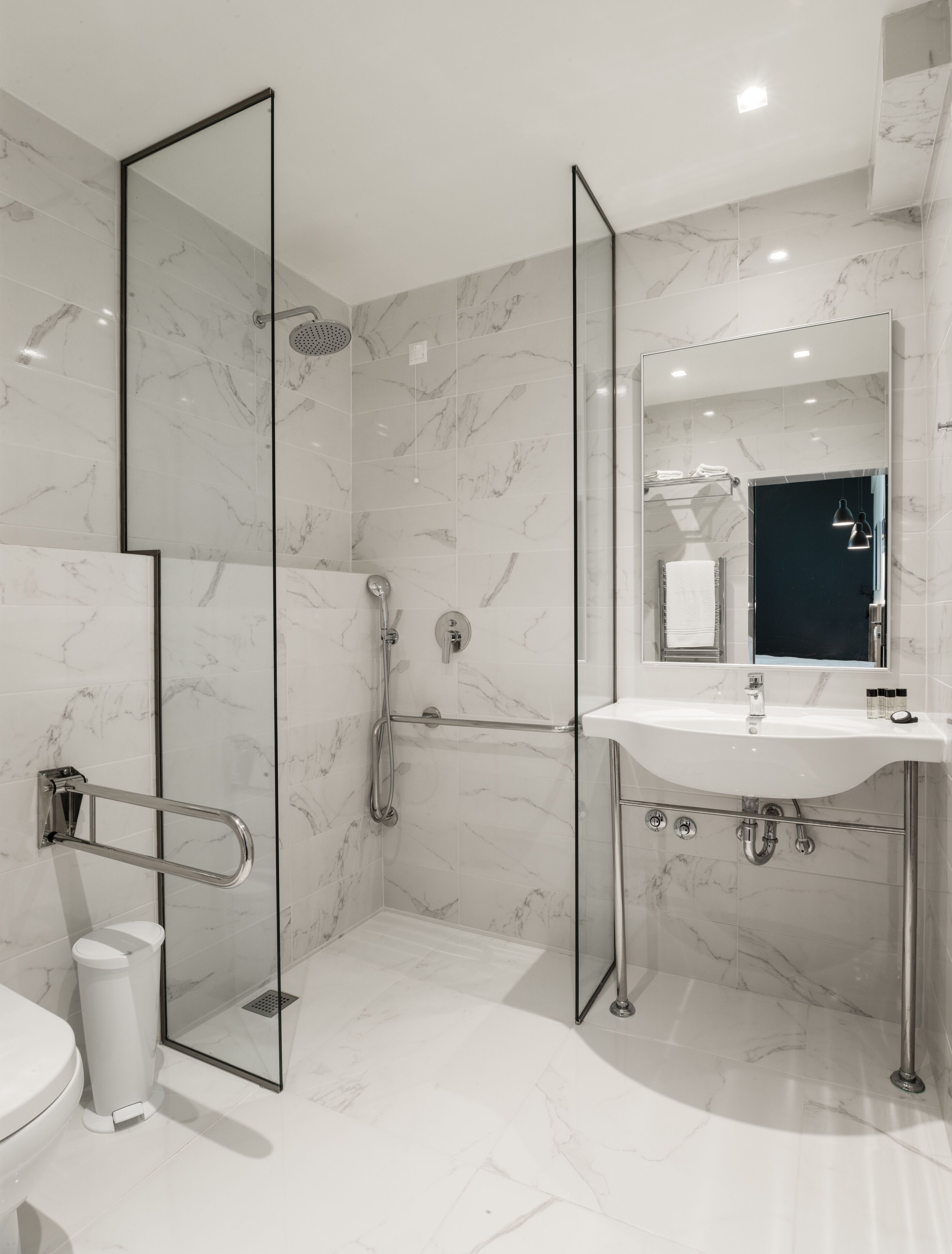 A modern bathroom with a glass-enclosed shower, a white sink, and a large mirror.