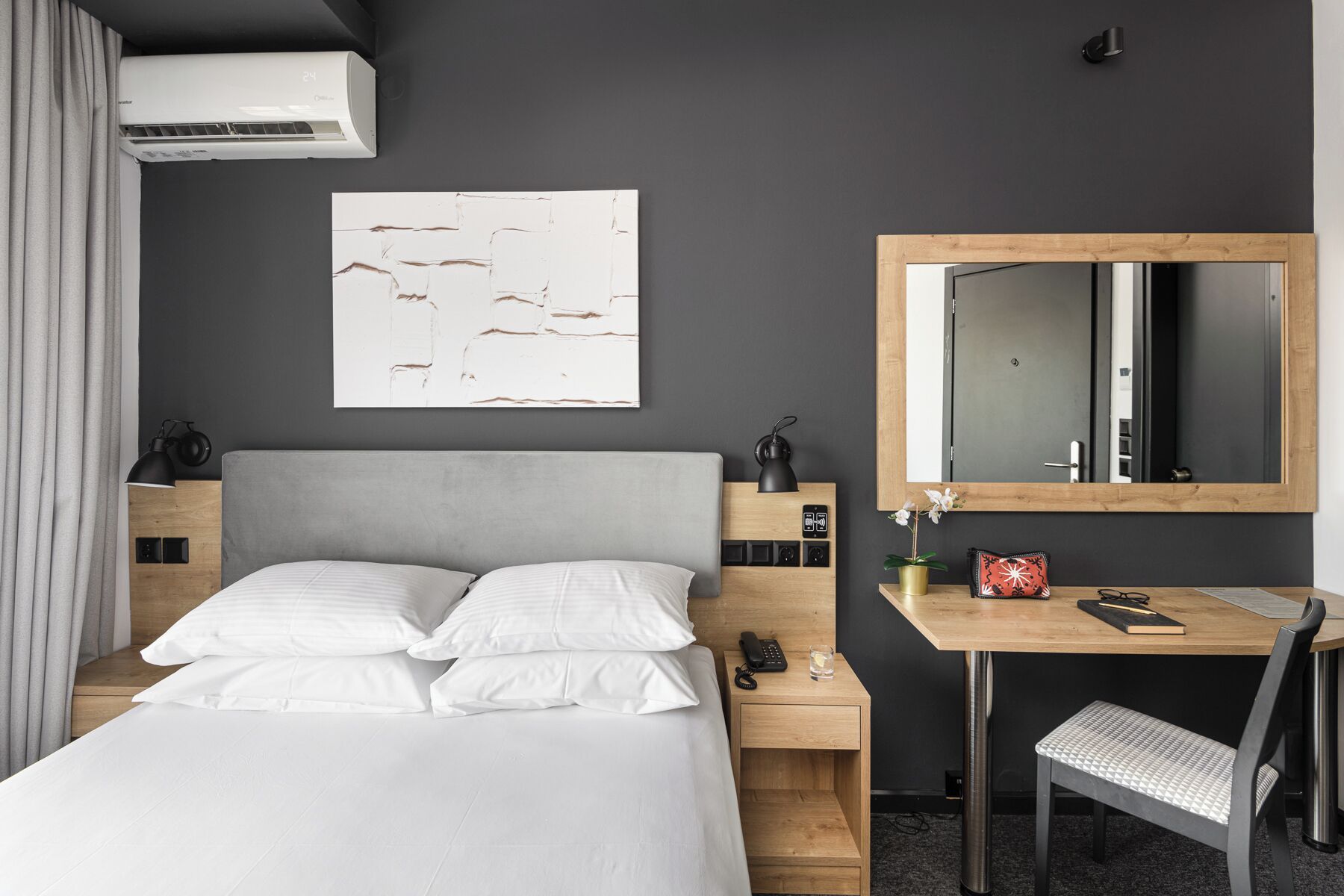 Una habitación de hotel moderna con una cama grande, un escritorio y un espejo.