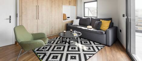 A modern living room with a grey sofa, a green armchair, and a patterned rug.