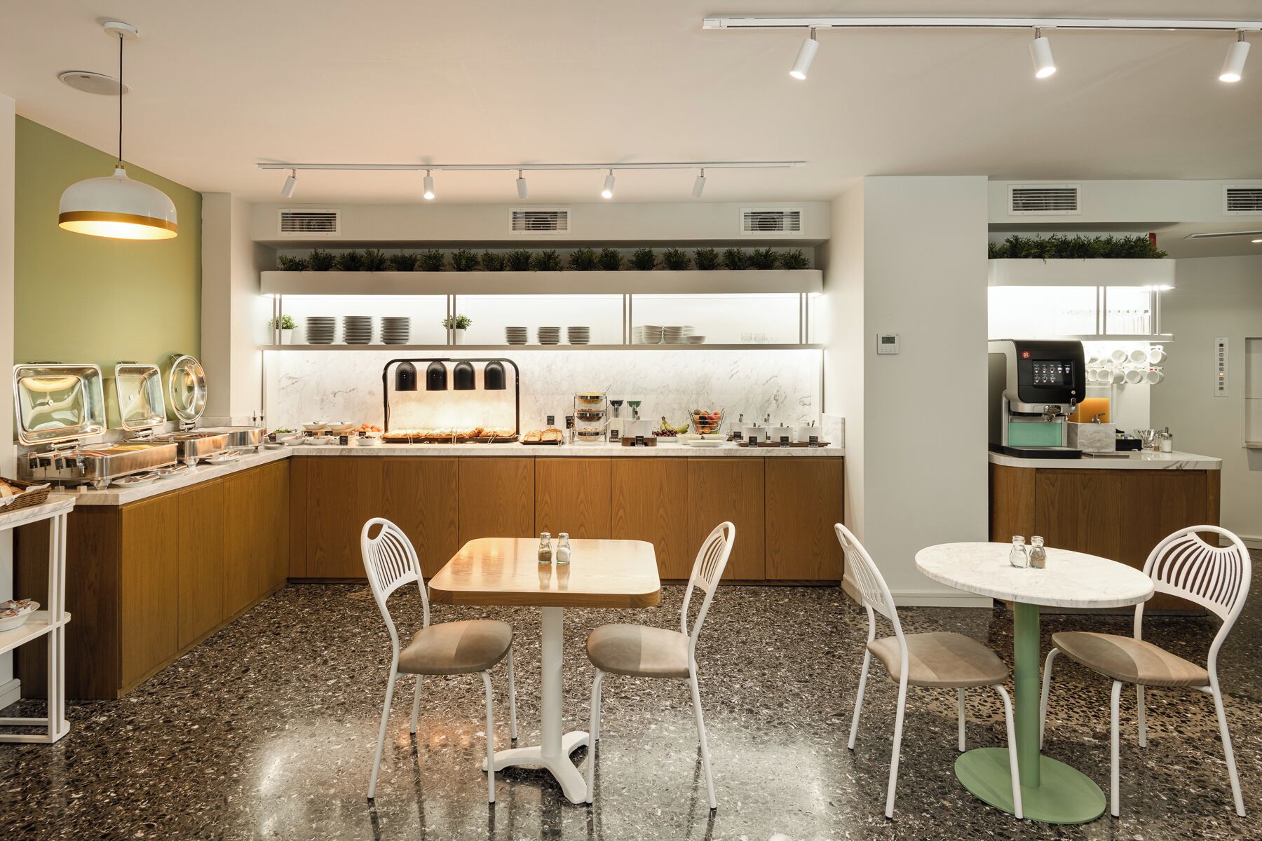 A modern kitchen with a central island, a dining area with four chairs, and a coffee machine.
