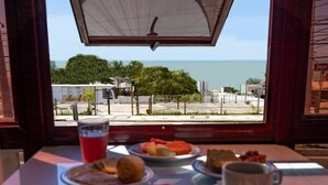 A table with breakfast items and a view of the beach. - Happy Ponta Negra Express (Natal)