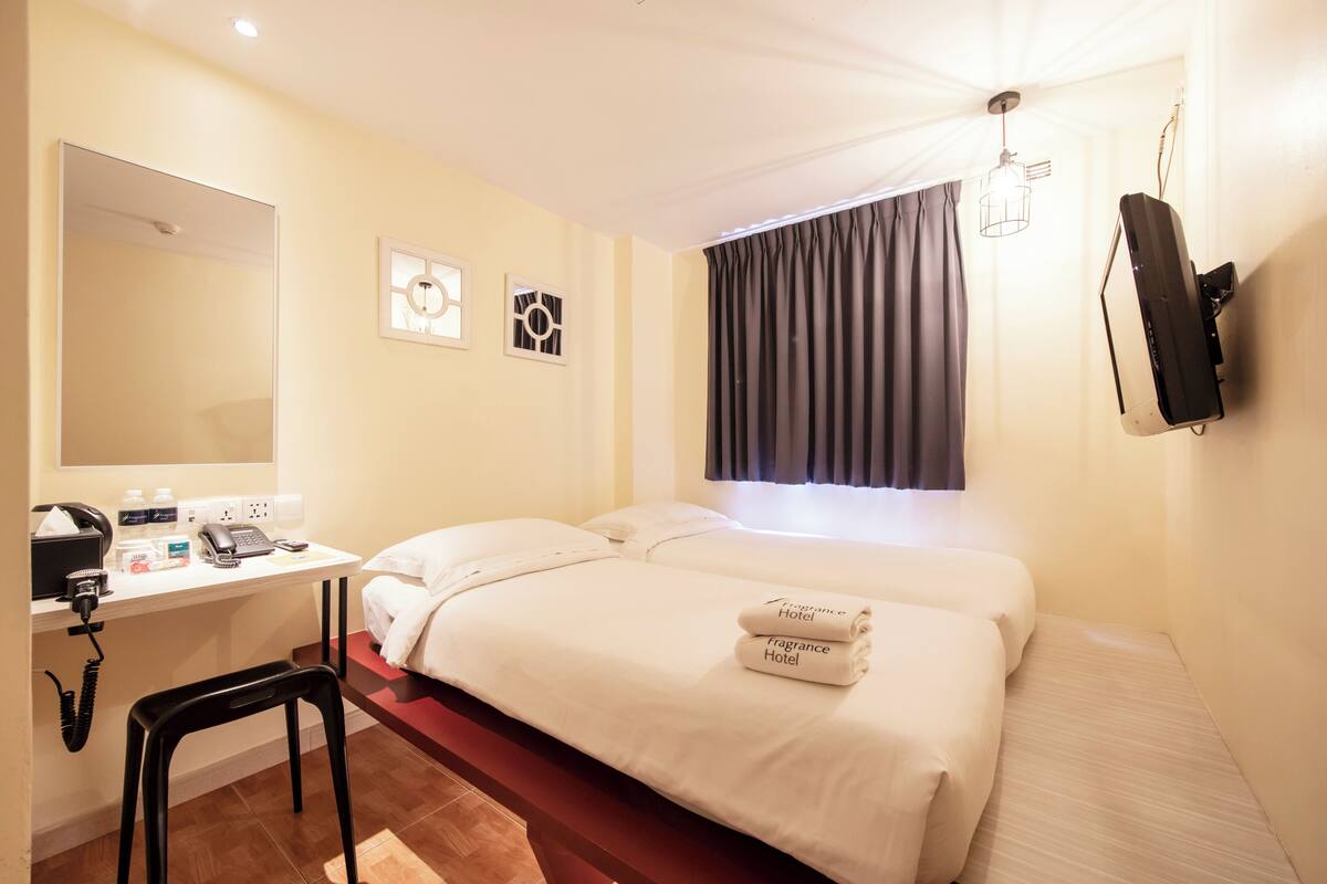 Une chambre d’hôtel avec un lit, un bureau avec un téléphone et un miroir.