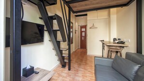 A modern living space with a staircase, a flat-screen TV mounted on the wall, a dining area with a table and chairs, and a sofa. - Fragrance Hotel - Balestier (Singapore)