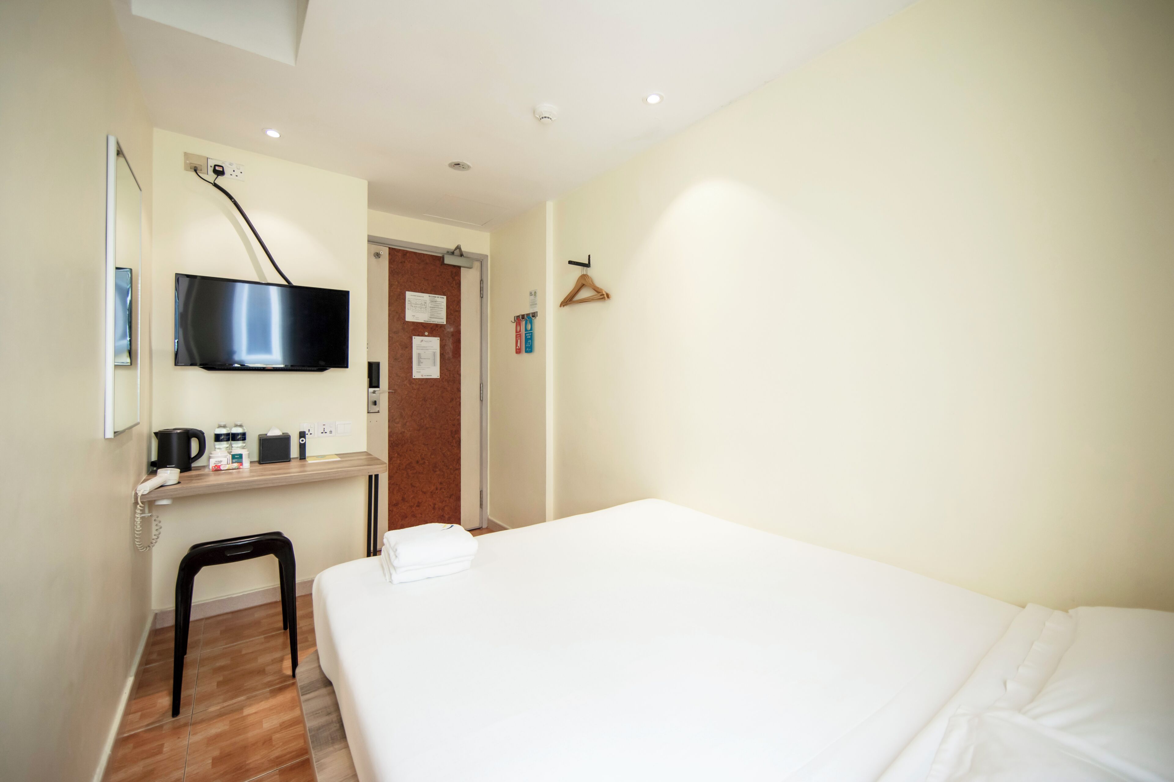 A hotel room with a bed, a desk with a flat-screen TV, a coffee maker, and a telephone.