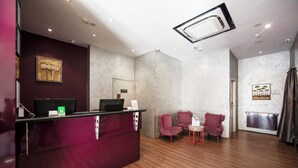 A reception area with a desk, chairs, and artwork on the walls. - Fragrance Hotel - Balestier (Singapore)