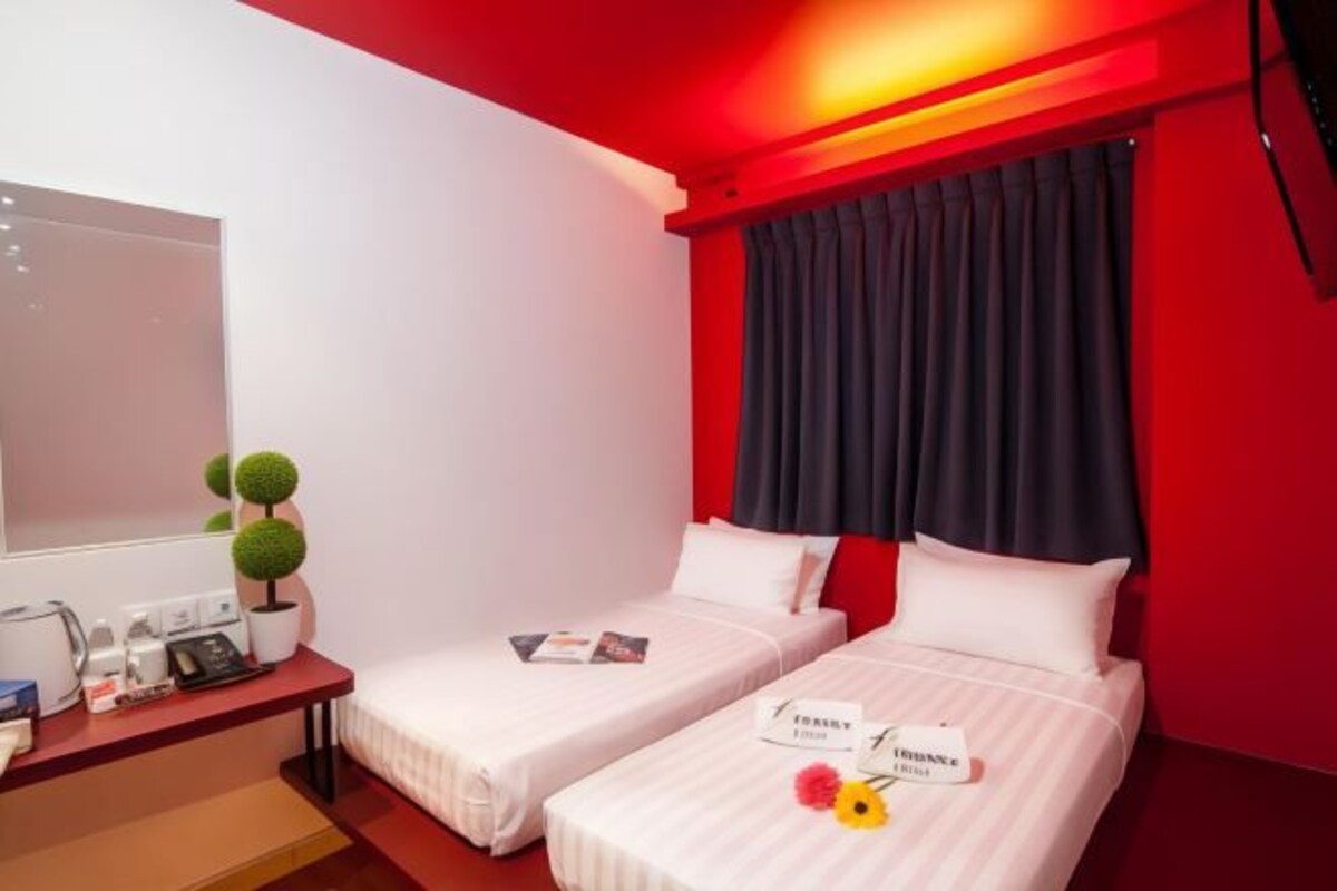 Une chambre d’hôtel avec deux lits, un bureau avec un téléphone et une petite plante en pot.