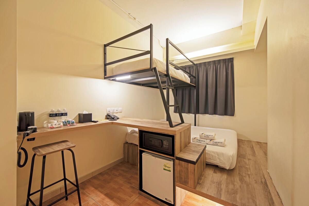 Une chambre d’hôtel compacte comprenant un lit superposé, une petite kitchenette, un bureau et un réfrigérateur de petite taille.