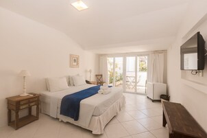 A bedroom with a bed, a nightstand, a lamp, a bench, a TV, and a sliding glass door leading to an outdoor area.