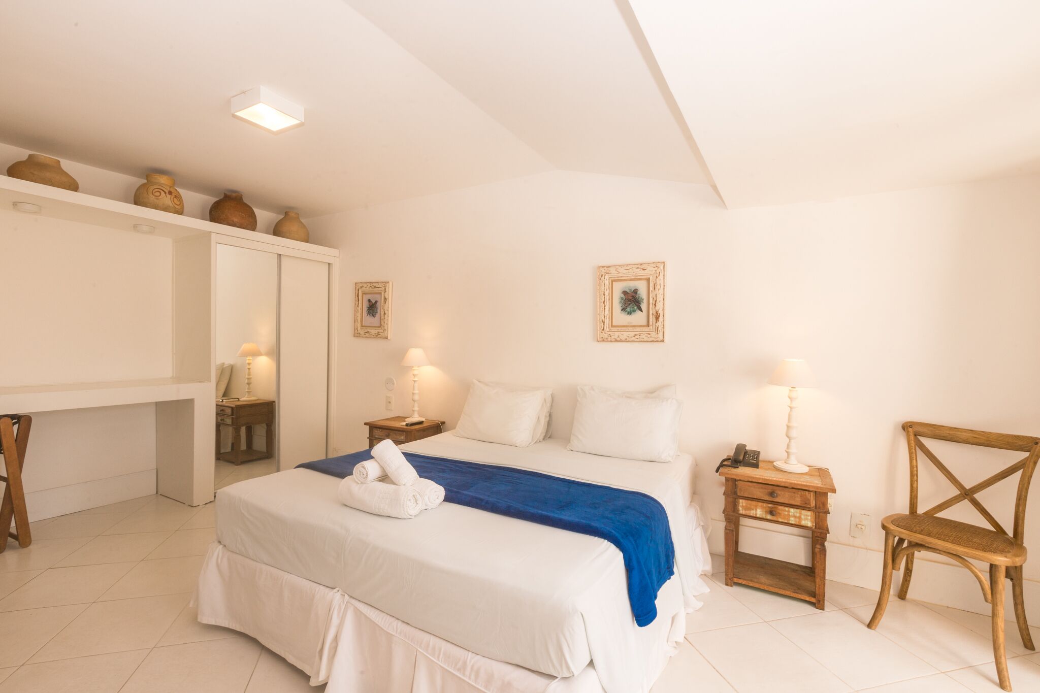 A bedroom with a bed, bedside tables, a chair, and decorative items on the wall.